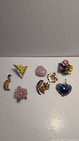 Lot overview showing various pins, brooches, and pendants arranged on a white surface.