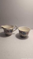 Photo showing the creamer and sugar bowl with floral designs from a front view