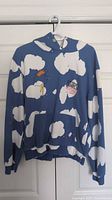Front view of blue hoodie with white cloud pattern hanging on hanger