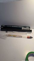 Two glass brewing thermometers including alcohol hydrometer and glass thermometer with protective boxes.