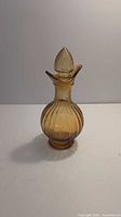 Full view of amber glass cruet with stopper, showing ribbed pattern and shape.