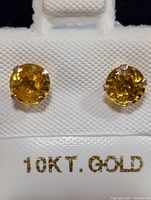 Front view of the 10K gold earrings with yellow sapphires on a white display card marked '10KT GOLD'.