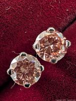 Close-up front view of both stud earrings on red velvet