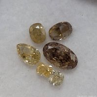 Six loose fancy color diamonds on white background, various shapes and colors