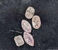 Five loose mixed-shape diamonds on black velvet background