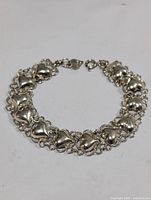 Silver bracelet laid flat showing heart-shaped links and clasp details.