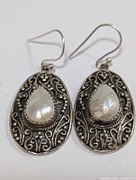 Front view of the silver earrings showing detailed filigree and teardrop pearl centerpiece