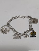 Top view image showing the full charm bracelet laid flat with all attached charms visible, including Canada bear charm and Calgary enamel charm.