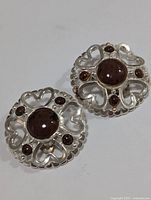 Front view of the silver earrings showing the open heart design and brown gemstones