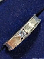 Close-up angled view of silver ring showing the clear round stone set in the band.