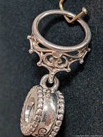 Close-up angled photo of the sterling silver pendant showing upper filigree design and hanging circular element with beaded edges.