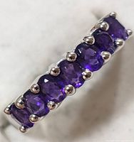 Close-up of top view showing seven oval-cut amethyst stones prong set in silver band.