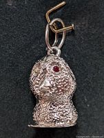 Clear image of silver textured animal or humanoid head pendant showing red stone eye and loop with ring attachment