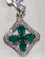 Clear photo of the silver pendant displaying the green onyx stones in cross formation with clear stones on frame