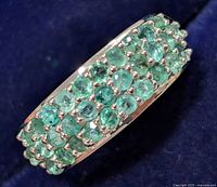 Close-up of the front view showing three rows of round emerald stones set in silver.