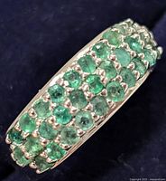 Close-up top view showing three rows of small round emerald stones set in silver.