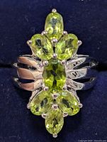Front view of sterling silver ring with five prong-set oval peridot stones forming a floral pattern on the band