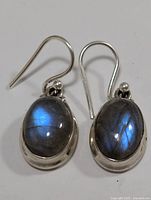 Front view of both earrings showing oval labradorite stones and sterling silver hooks.