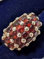 Top angled close-up showing the garnet stones with silver bead prongs and the dome cluster style of the ring.