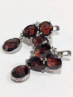 Top view of a single garnet earring showing the cluster arrangement of garnet stones and clear accents in sterling silver.