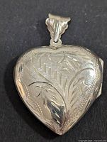Front view of silver heart-shaped locket pendant with engraved floral and leaf pattern