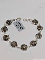 Silver bracelet made of linked circular bezels containing polished pink Mohave turquoise stones, showing natural matrix inclusions and variations in color.