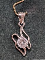 Close-up photo of the silver pendant with clear round cubic zirconia stone highlighting the abstract design and bail detail