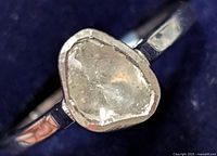 Close-up view of the silver ring's diamond top showing the rough diamond shape and bezel setting.