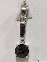 Close-up front view of silver pendant with garnet stones, showing round and rectangular garnets