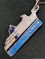 Front close-up of silver pendant shaped as the M.S. Chi-Cheemaun ship with blue and yellow enamel accents.