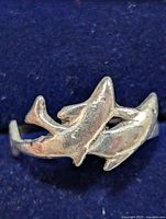 Front view of silver dolphin ring showing two dolphins wrapped around the band.