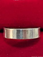 Front view of silver ring, showing flat smooth band and brushed texture.
