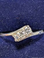 Close-up photo of silver ring showing five clear stones set on a raised rectangular portion of the band.
