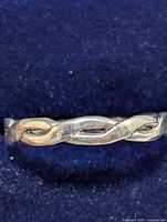 Close-up image showing the twisted, intertwined design of the silver ring and its polished finish with surface wear.