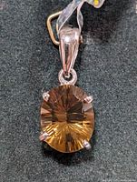 Front view of silver pendant with oval faceted smokey quartz set with four prongs.