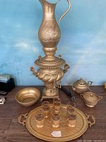 Full set displayed on wooden surface showing all components including electric samovar, pitcher, creamer, sugar bowl, metal bowl, tray with six drinking glasses.