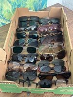 Box containing 30 pairs of assorted used sunglasses in mixed frame styles and colors