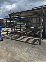 Photo showing a side view of heavy duty pallet racking with metal frame and multiple levels of shelving outdoors