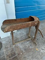 Side view of the antique corn or sugarcane chopper showing the wooden trough and frame.