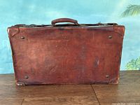 Bottom view of antique leather suitcase showing worn leather surface and some scuffing.