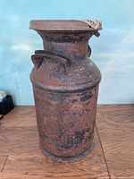 Metal milk container with visible rust and wear, showing overall heavy use condition.
