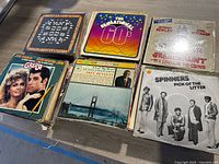 Six vinyl records on display including The Sensational 60s, Grease soundtrack, and Spinners - Pick of the Litter.
