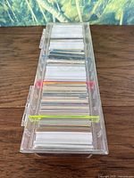 Top view of clear plastic case with multiple stacks of mixed trading cards inside separated by colored separators.