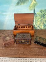 Four wooden decorative boxes including one open rectangular box with compartments and three smaller boxes with carved, metal, and painted designs.