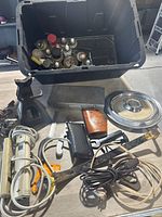 Photo of extension cords, tools, car hubcap, and other miscellaneous automotive accessories spread in front of the box