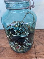 Blue glass jar filled with assorted jewelry and accessories viewed from one side
