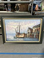 Full view of the framed oil painting depicting a fishing shrimping boat docked at a wooden pier with buildings, showing overall scene and condition.