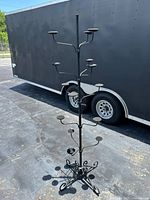 Full view of black metal hat display rack showing height and multiple padded round holders
