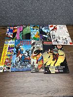 Top-down view of the 11 comic books laid out on a table with colorful covers showing various superheroes such as Captain America, Deadpool, Batman, and Justice League.