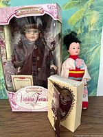 Boxed Victorian Treasures porcelain doll alongside Asian-style doll and small boxed doll figurine.